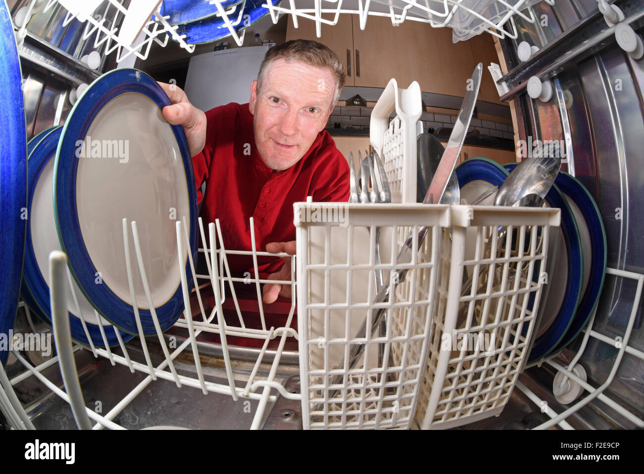 L uomo lo scarico di pulire le piastre dalla lavastoviglie in cucina Foto Stock