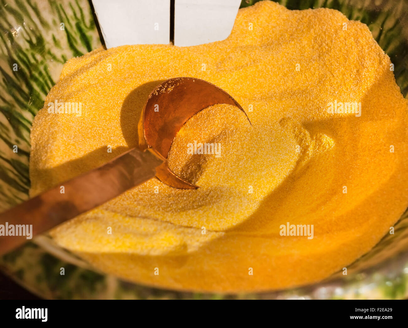 Chiusura del cucchiaio di rame nella ciotola di polenta raw Foto Stock