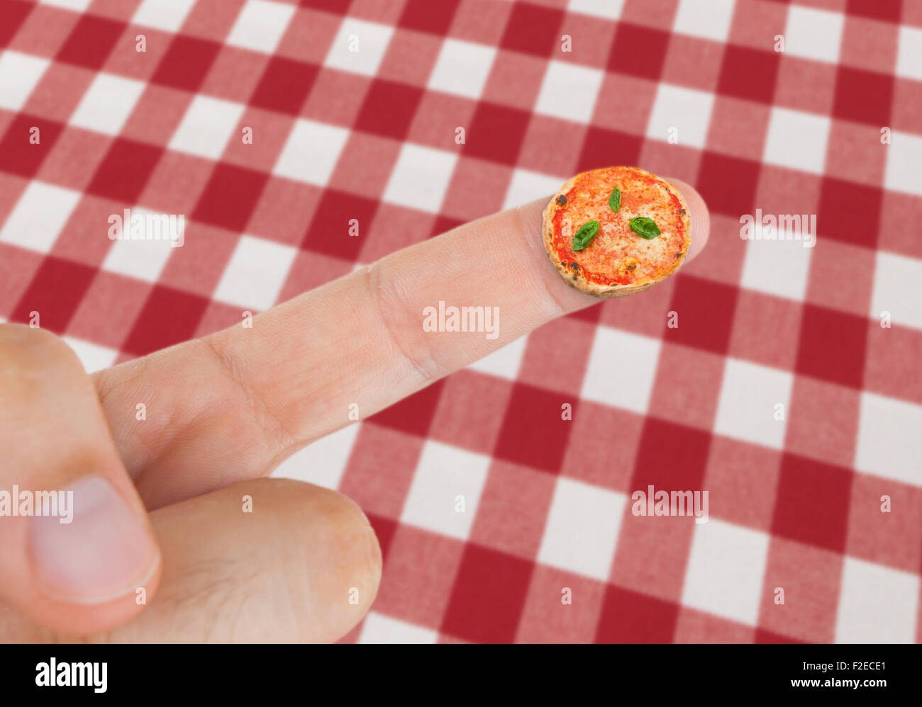Il piatto con la pizza margherita in miniatura sul dito con tovaglia rosso con motivo a scacchi. Foto Stock