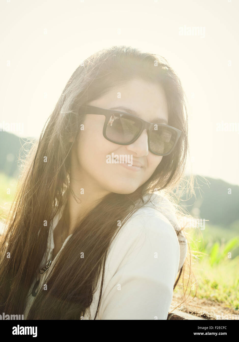 Ritratto di un adolescente con occhiali da sole fotografato in controluce Foto Stock