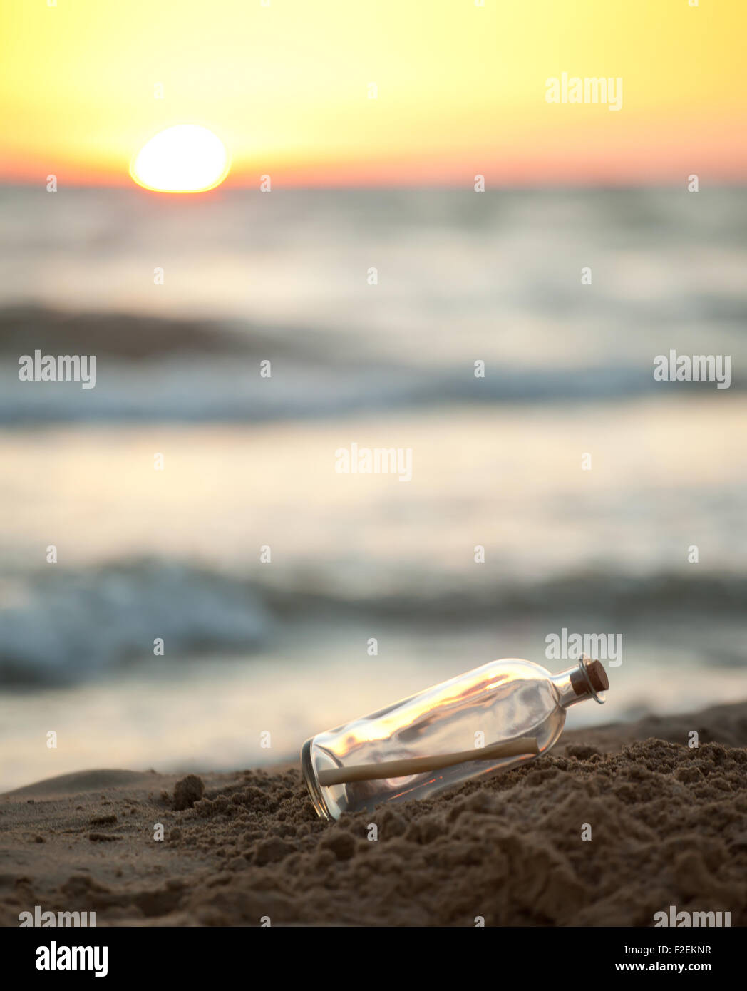 Messaggio in una bottiglia di vetro su una spiaggia con sunrise in background Foto Stock