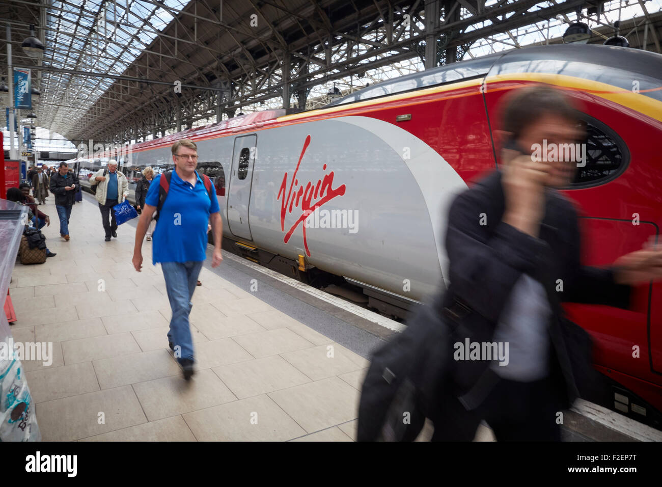 Stazione ferroviaria Manchester Piccadilly vergine logo su un treno pendolino da Londra passeggeri in transito a piedi sfocate per uomo Foto Stock