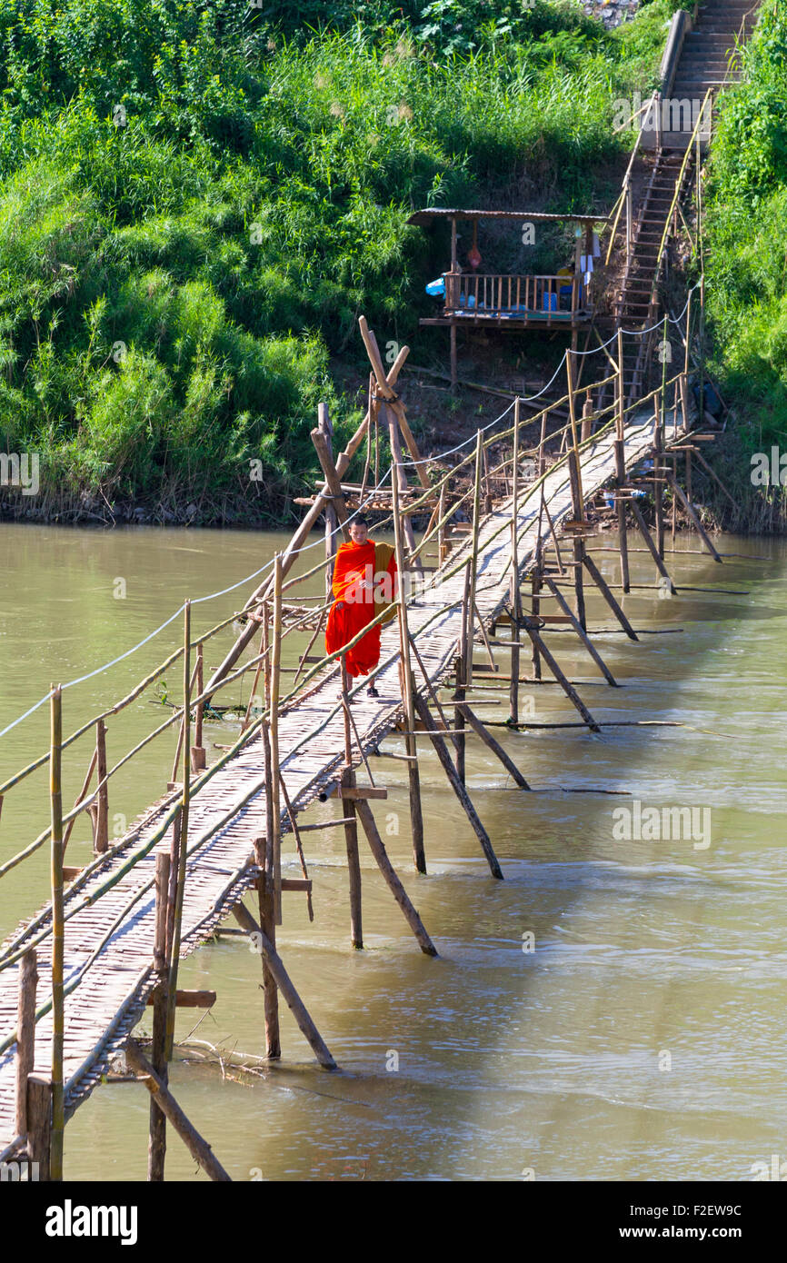 Monaco sul ponte pedonale di fronte fiume Nam Khan, Luang Prabang, Laos Foto Stock