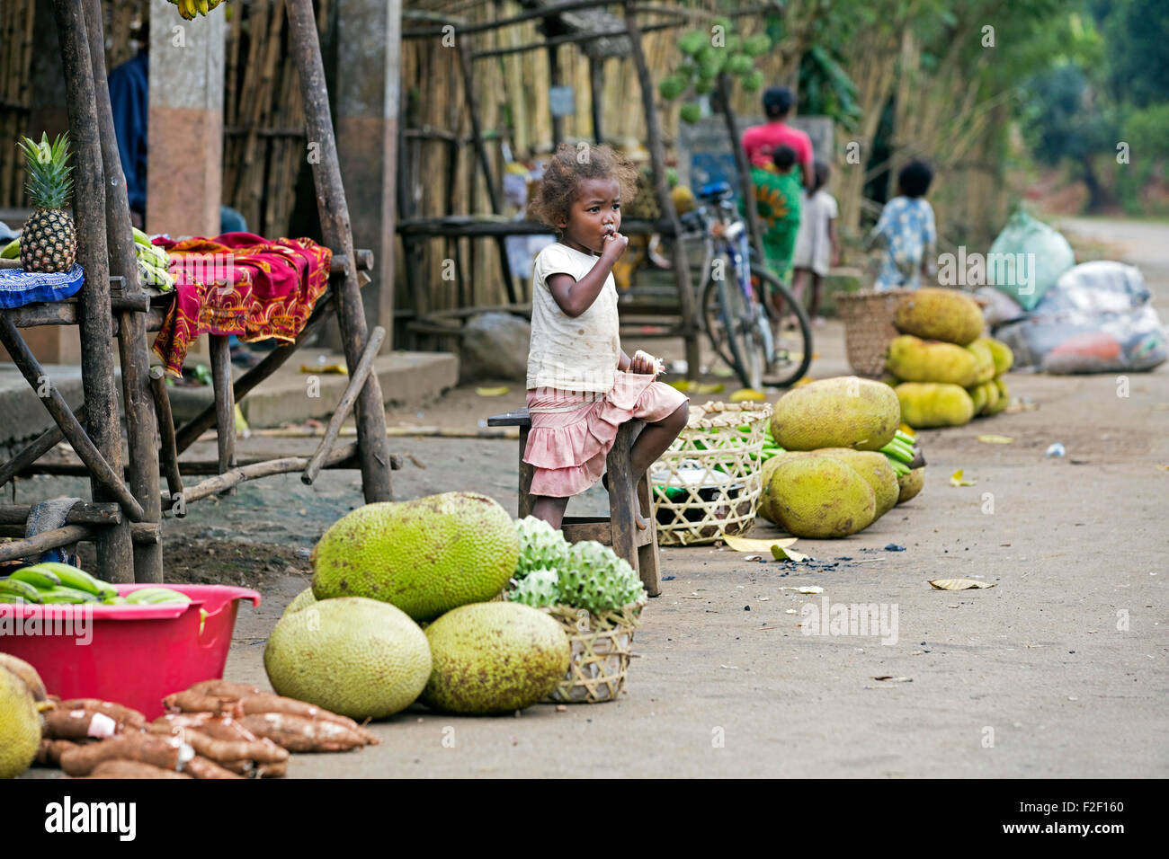 Un malgascio ragazza alla strada del mercato di vendita di stallo durian, jackfruit , verdure nel villaggio rurale di Vatovavy Fitovinany, Madagascar Foto Stock