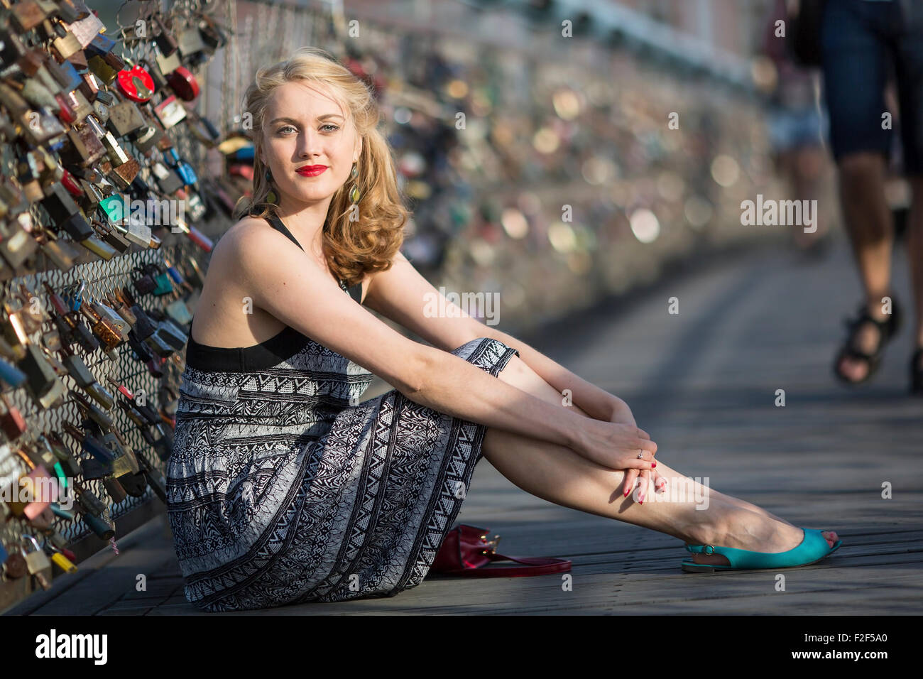 Piuttosto giovane donna seduta sul ponte di amore in Cracovia. Foto Stock