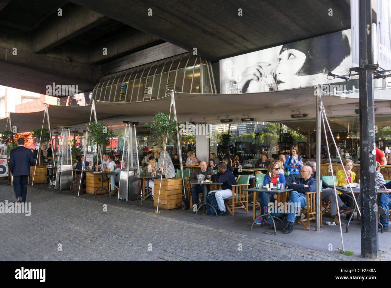 Persone mangiare fuori del National Film Theatre, sotto il ponte di Waterloo, sul London South Bank. Foto Stock