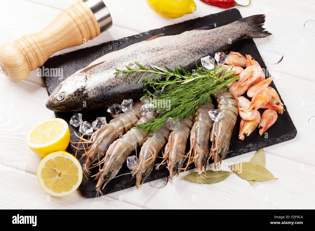 Crudo fresco il cibo del mare con spezie sulla lastra di pietra su un tavolo di legno dello sfondo. Vista superiore Foto Stock