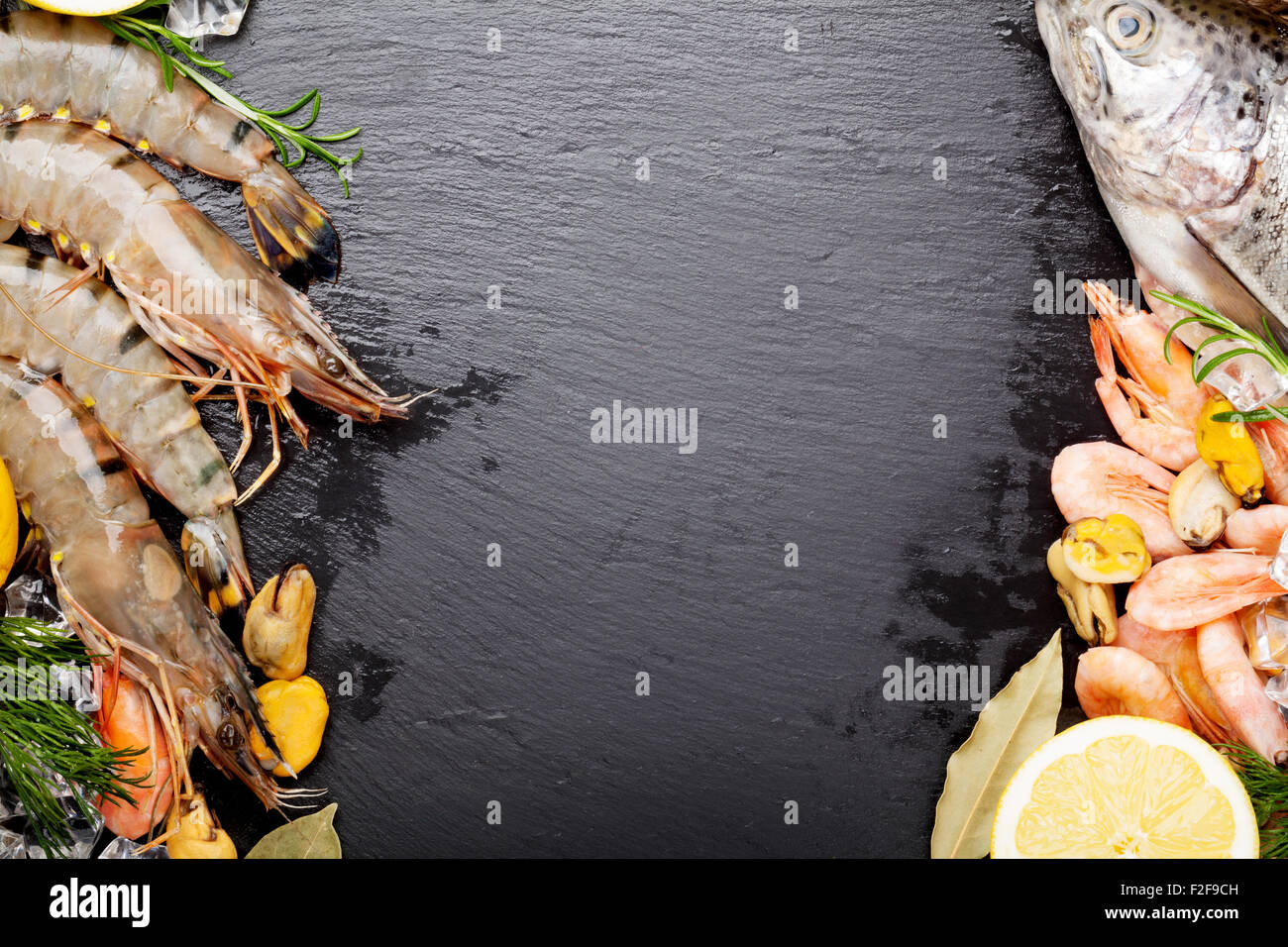 Crudo fresco il cibo del mare con spezie sulla pietra nera dello sfondo. Vista da sopra con lo spazio di copia Foto Stock