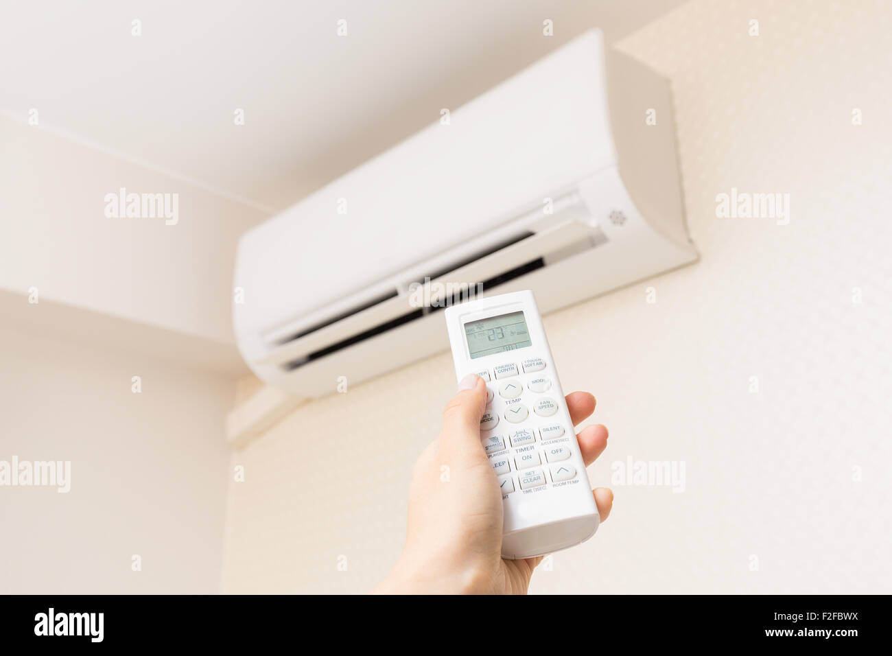 Mano con telecomando diretto sul condizionatore. Foto Stock