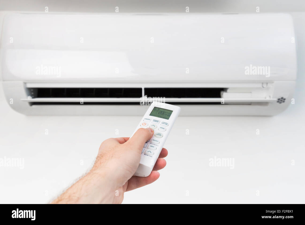 Mano con telecomando diretto sul condizionatore. Foto Stock