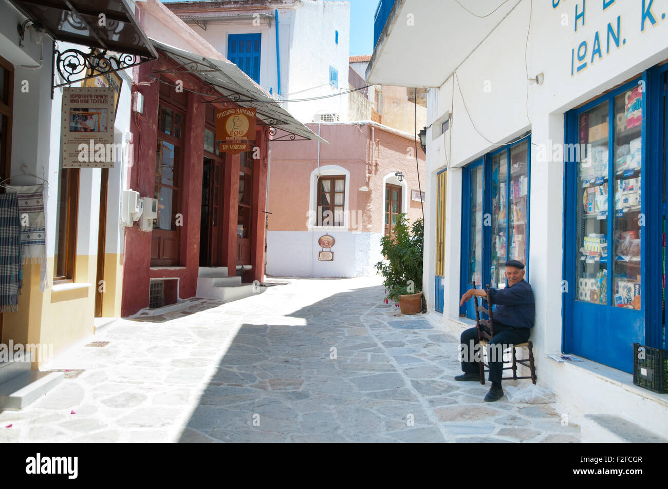 Il vecchio uomo seduto al di fuori del negozio nel villaggio di Chalki, isola di Naxos, Cicladi Grecia Foto Stock