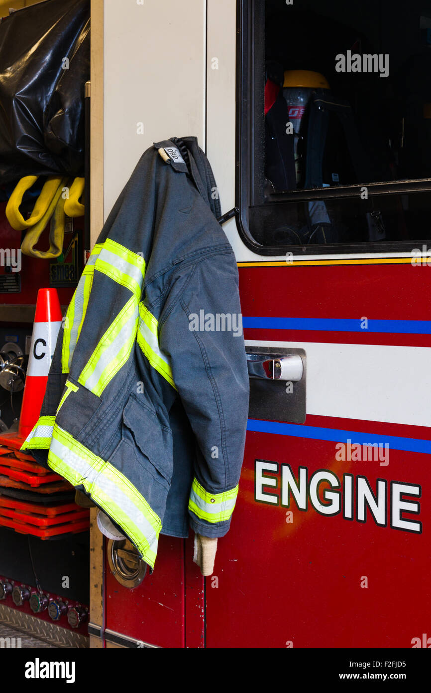 Vigili del fuoco camicia appeso sul fuoco carrello porta pronto per una chiamata di emergenza Foto Stock