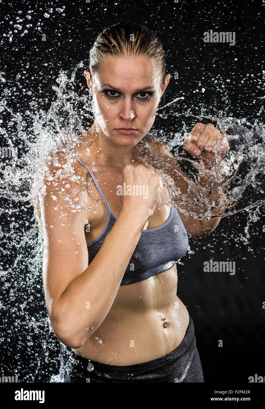 Athletic donna in combattimento pone a spruzzi d'acqua Foto Stock