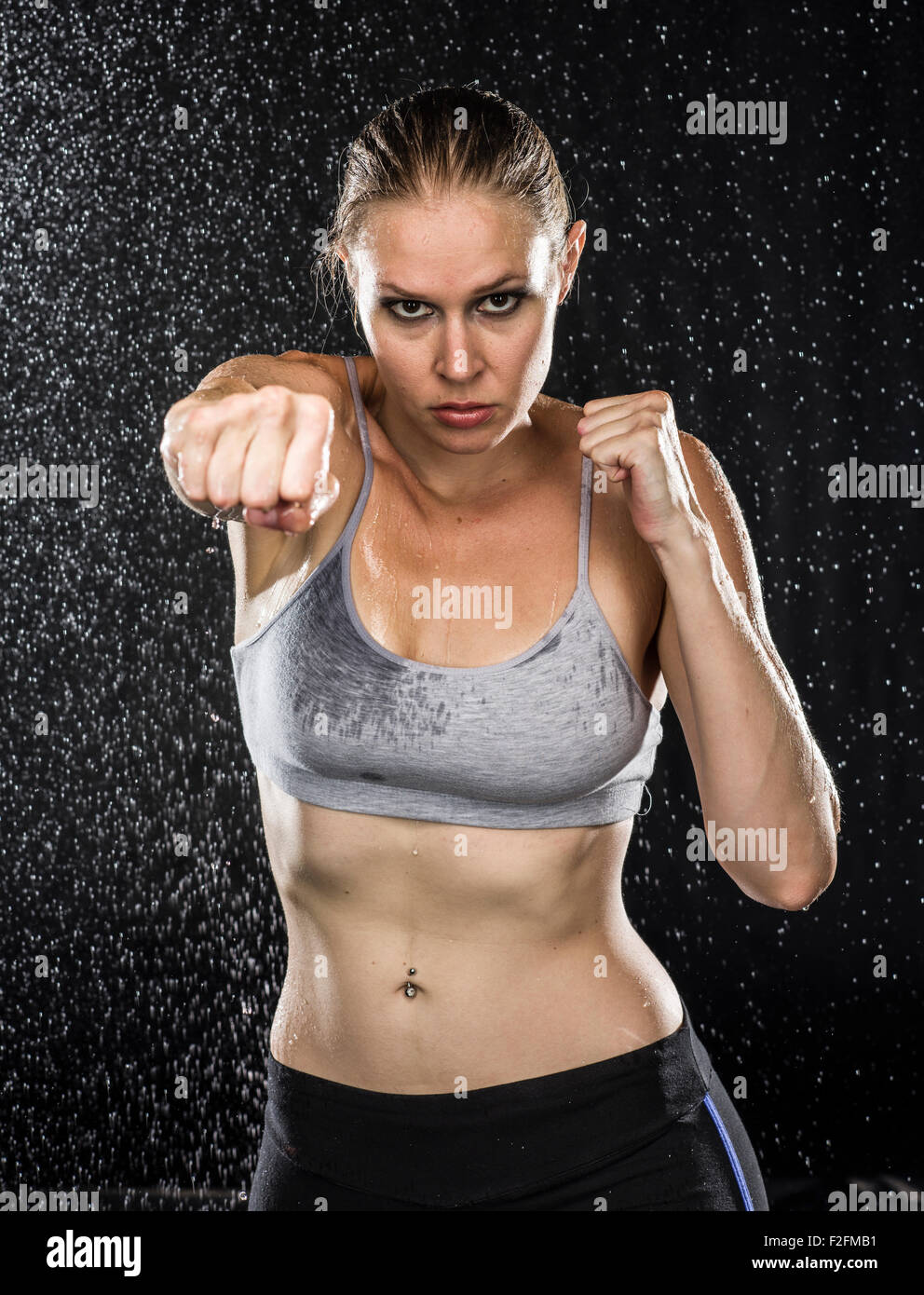 Montare la donna nella punzonatura pongono contro le gocce d acqua Foto Stock