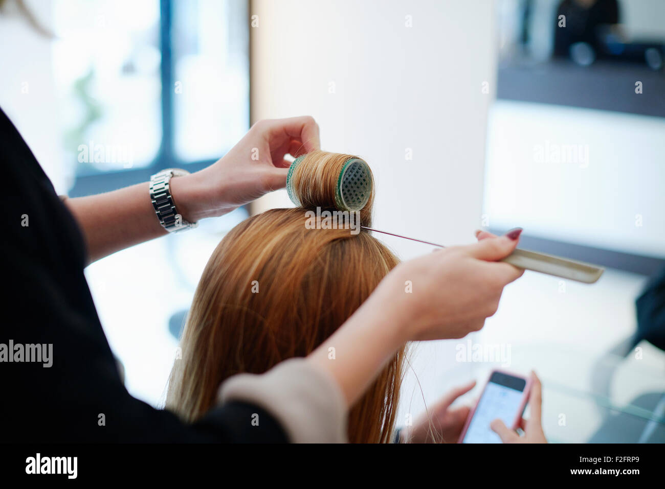 Parrucchiere incarto del cliente i capelli in bigodini in salone Foto Stock