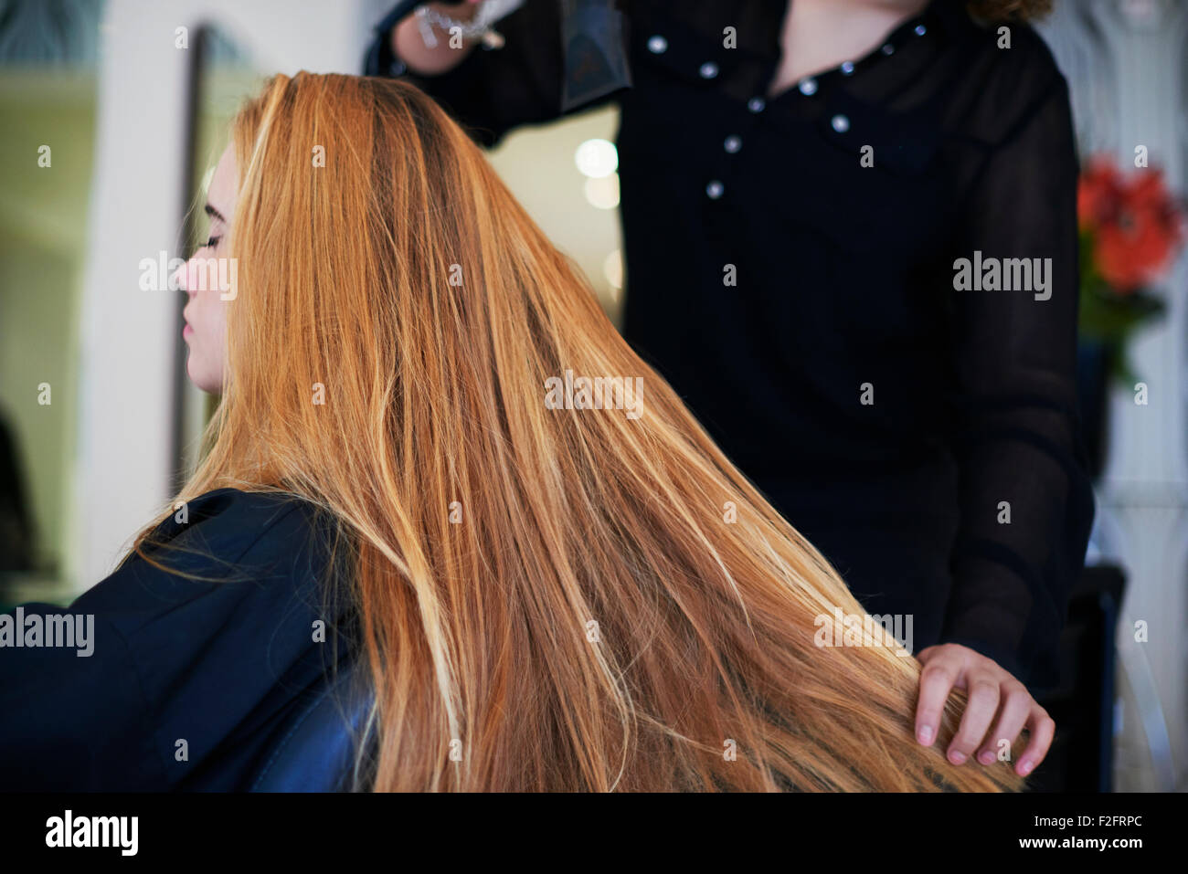 Parrucchiere essiccazione del cliente capelli lunghi in salone Foto Stock