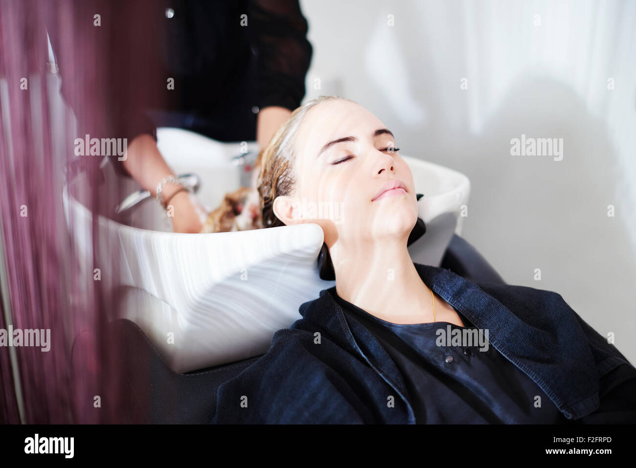 Cliente con gli occhi chiusi di ottenere capelli lavati in salone Foto Stock