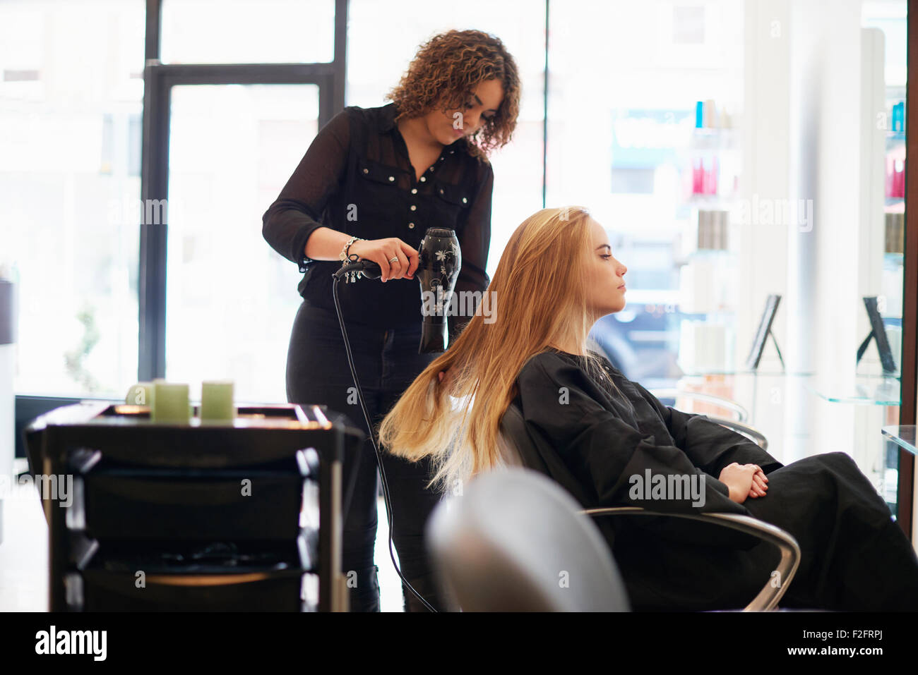 Parrucchiere essiccazione del cliente capelli lunghi in salone Foto Stock