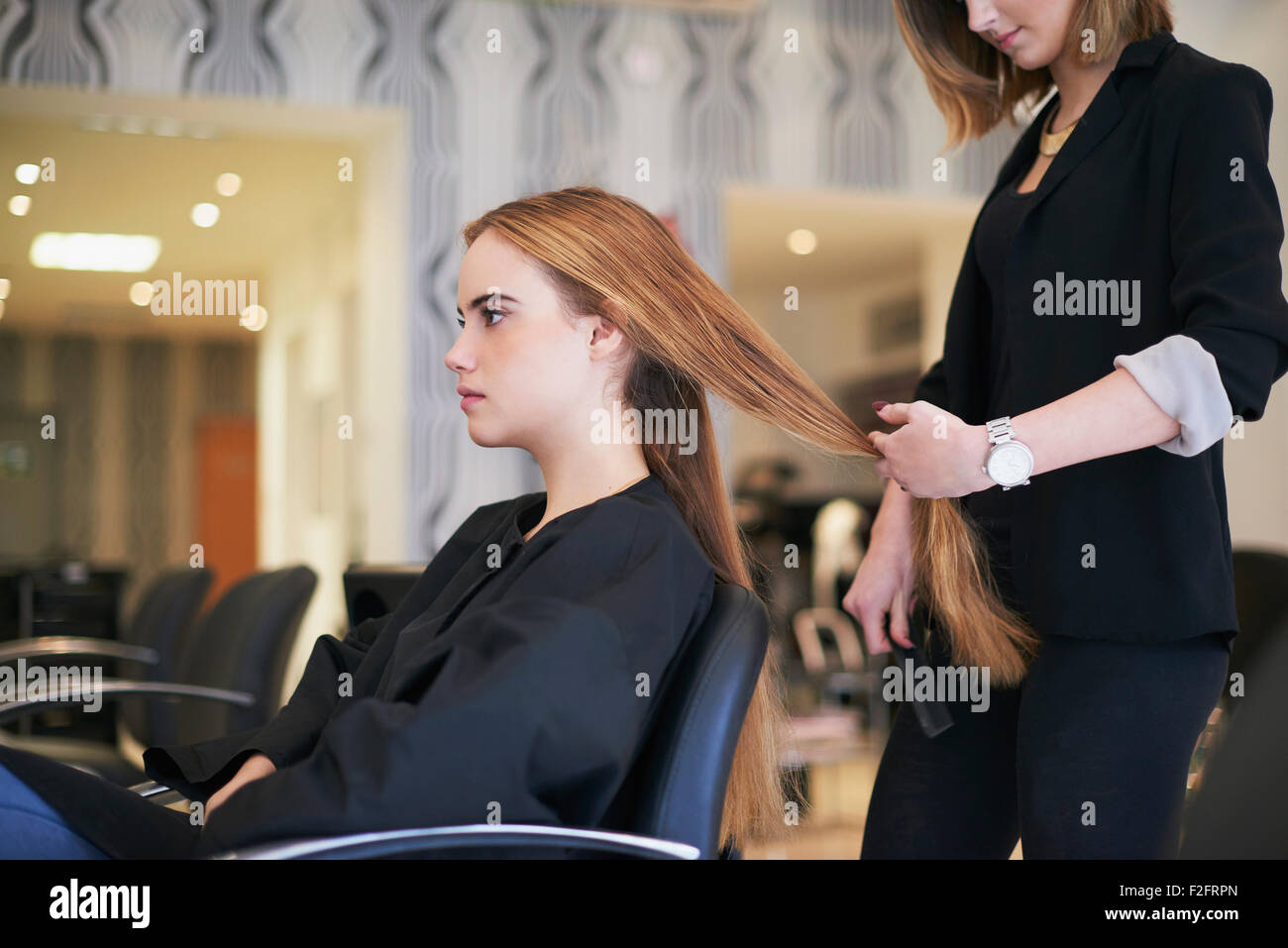 Parrucchiere preparazione al taglio del cliente capelli lunghi in salone Foto Stock