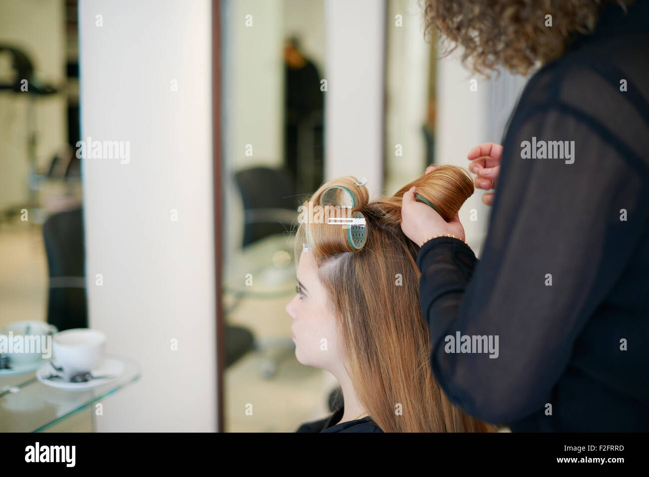 Parrucchiere il rotolamento del cliente in capelli arricciacapelli in salone Foto Stock