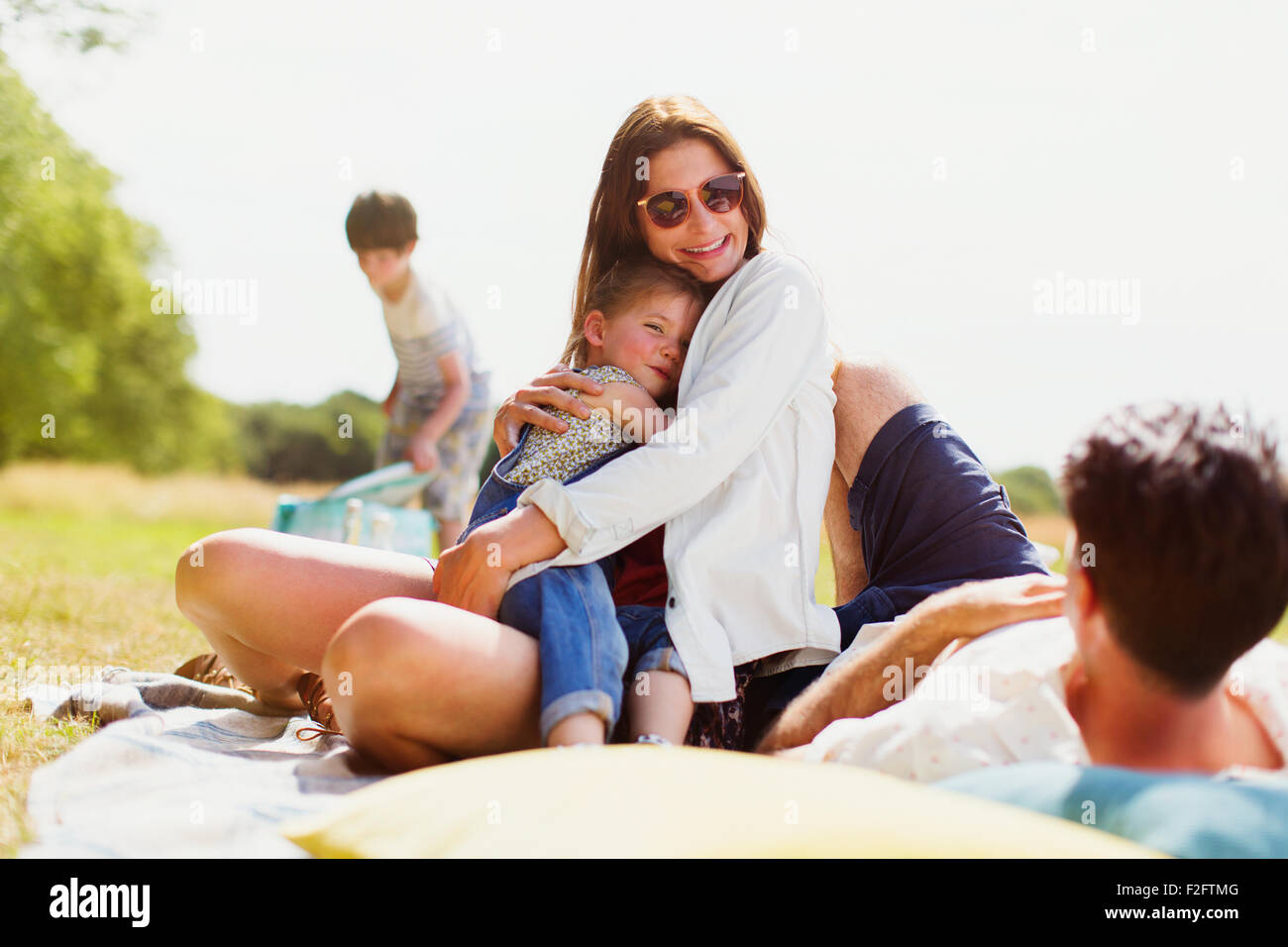 Famiglia relax su una coperta in campo soleggiato Foto Stock