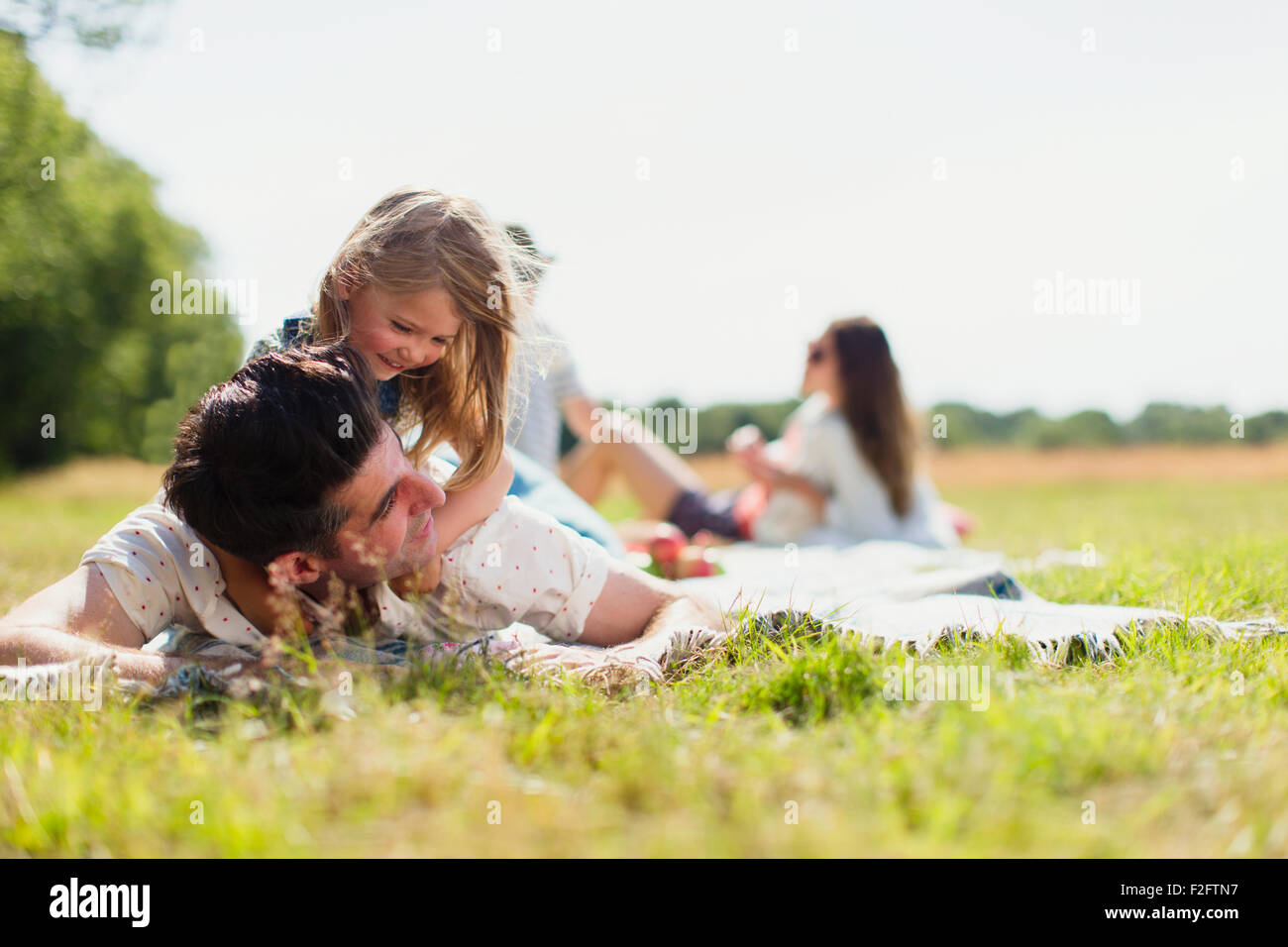 Affettuosa figlia recante sulla sommità del padre nel campo soleggiato Foto Stock