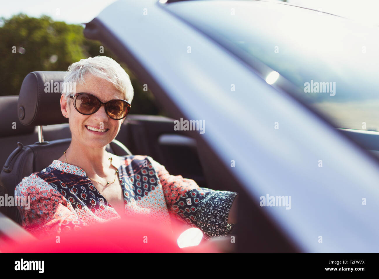 Ritratto sorridente donna senior in occhiali da sole convertibile di guida Foto Stock