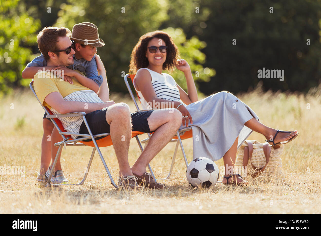 Famiglia sorridente rilassante nella soleggiata campo Foto Stock