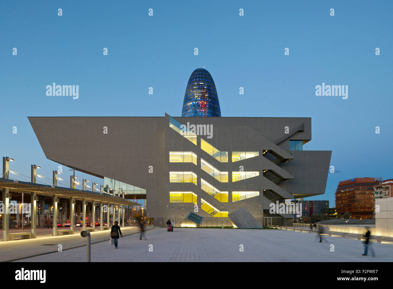 Crepuscolo elevazione con piazza pubblica e illuminato di museo. Museu del Disseny de Barcelona, Barcelona, Spagna. Architetto: farine di carne e di ossa Arquitecte Foto Stock