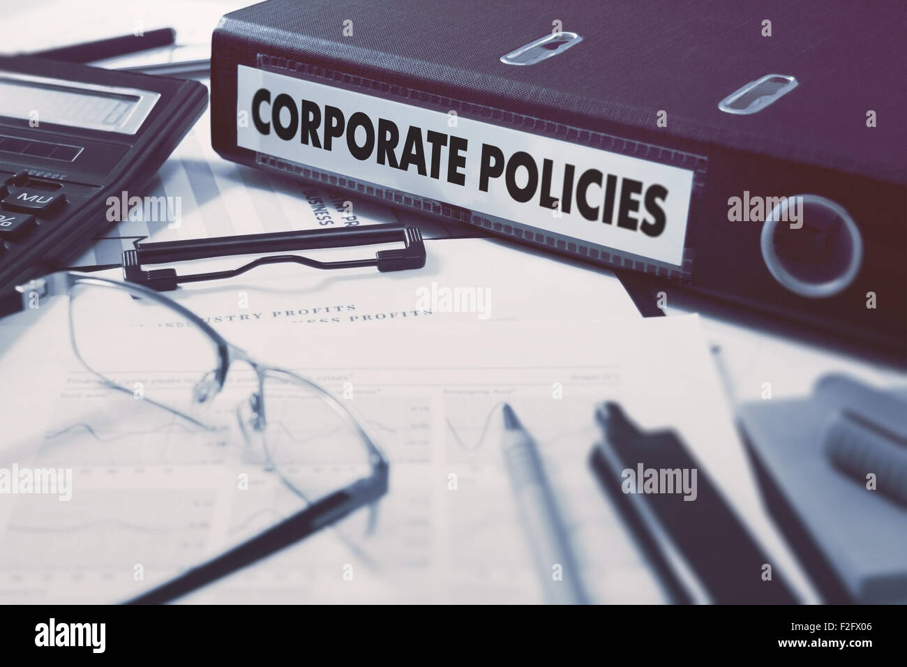 Le politiche aziendali - Ufficio cartella sullo sfondo del tavolo di lavoro con cancelleria, bicchieri, relazioni. Il concetto di business su sfocato Foto Stock