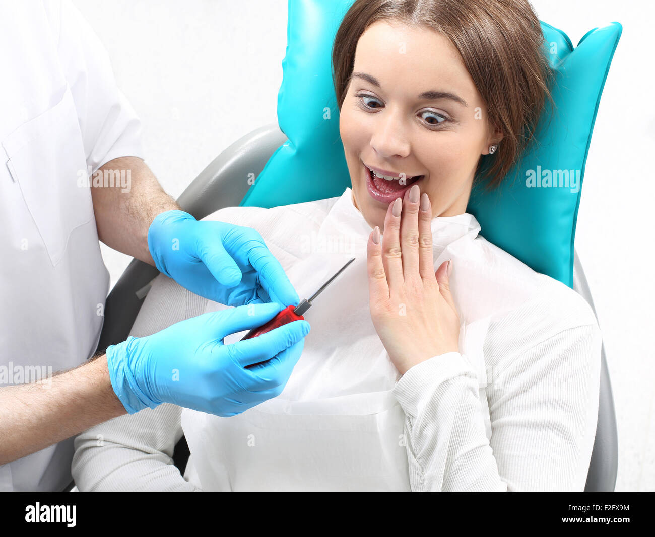 Frightened donna su una poltrona del dentista, paura del dentista Foto Stock