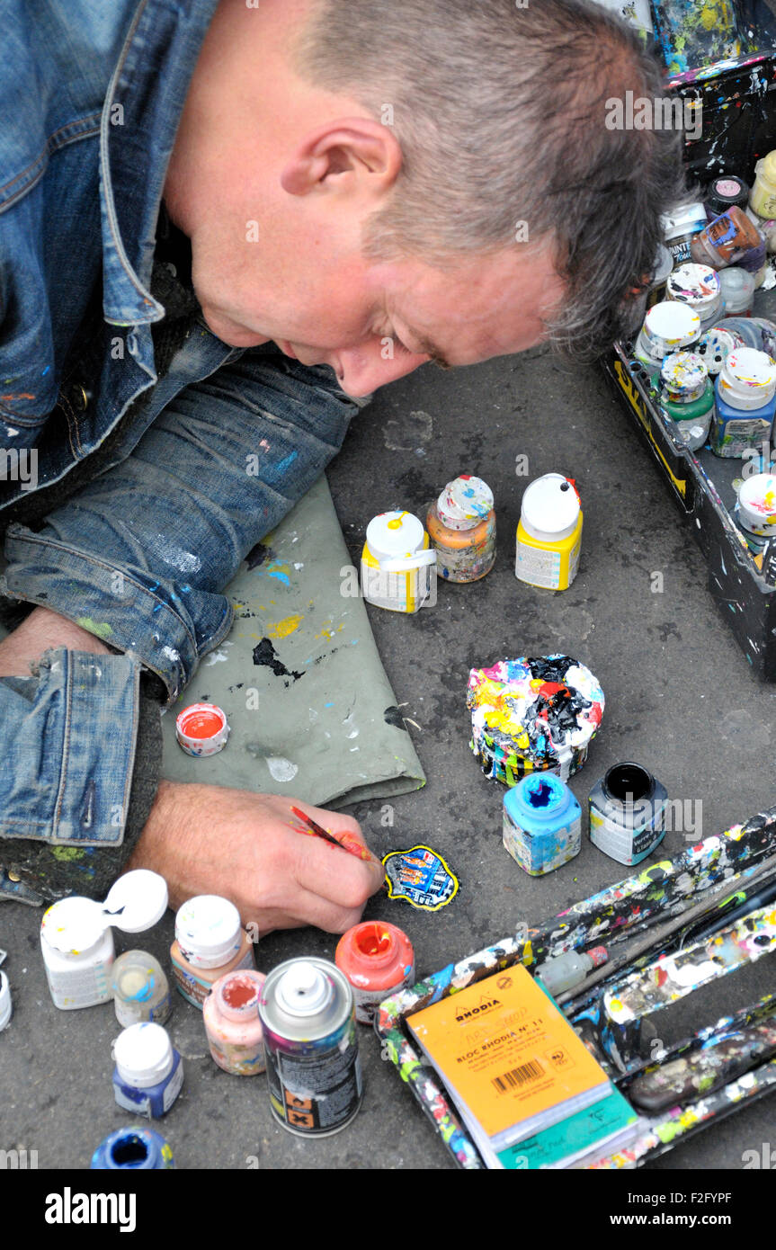 Ben Wilson "chewing gum Man' verniciatura di un piccolo lavoro di arte su un scartato pezzo di gomma sul marciapiede da Tottenham Court Rd tubo Foto Stock