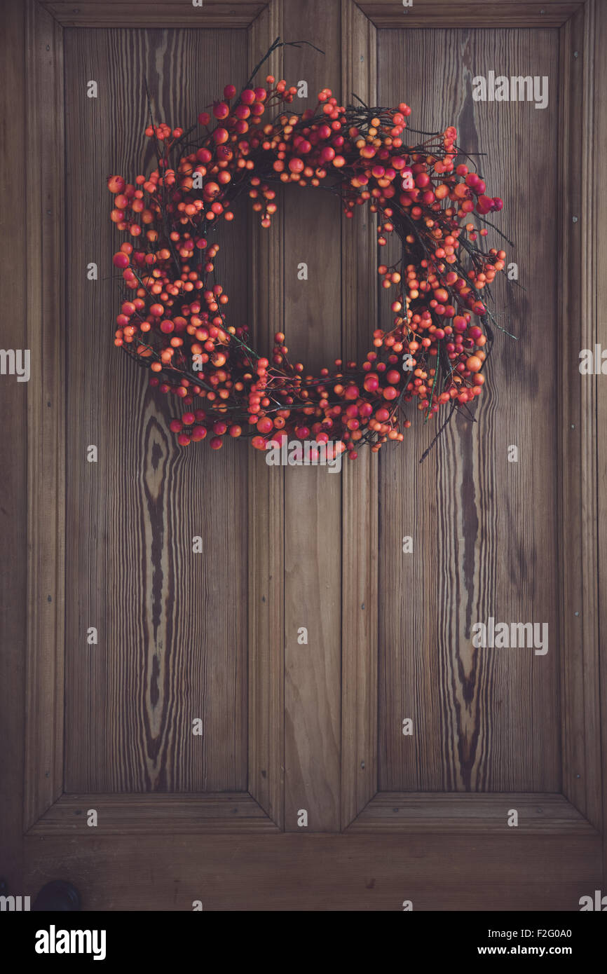 Caduta berry corona appeso su una porta di legno Foto Stock