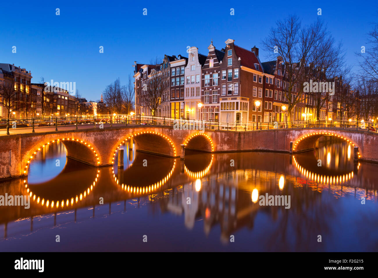 Ponti su un incrocio di canali della città di Amsterdam, Paesi Bassi durante la notte. Foto Stock