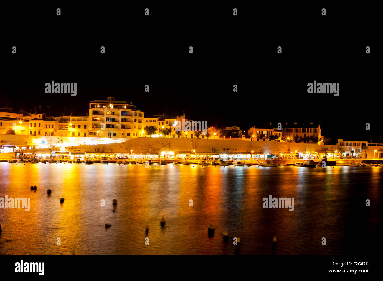 El Castell minorca Harbourside di notte luci che riflettono in acqua barche ed edifici Foto Stock