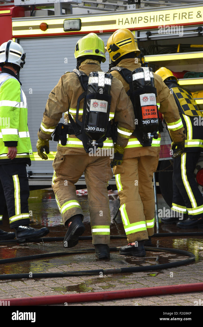 Vigile del fuoco in apparecchi di respirazione a fianco di un incendio al motore durante un incendio Foto Stock