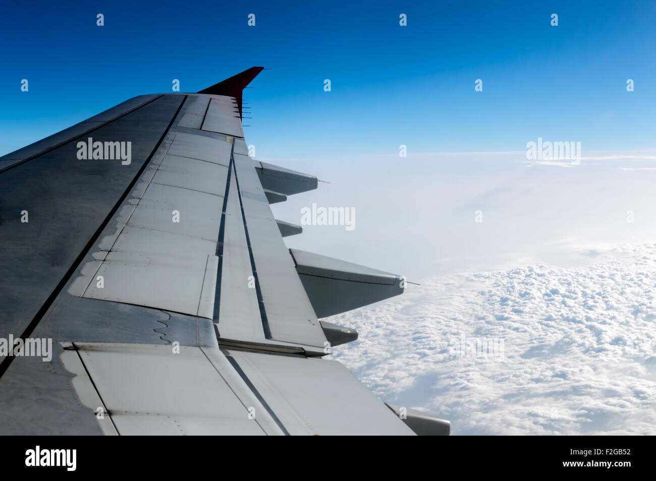 Cielo nuvoloso e ala di aeroplano come visto attraverso la finestra di un aeromobile. Foto Stock