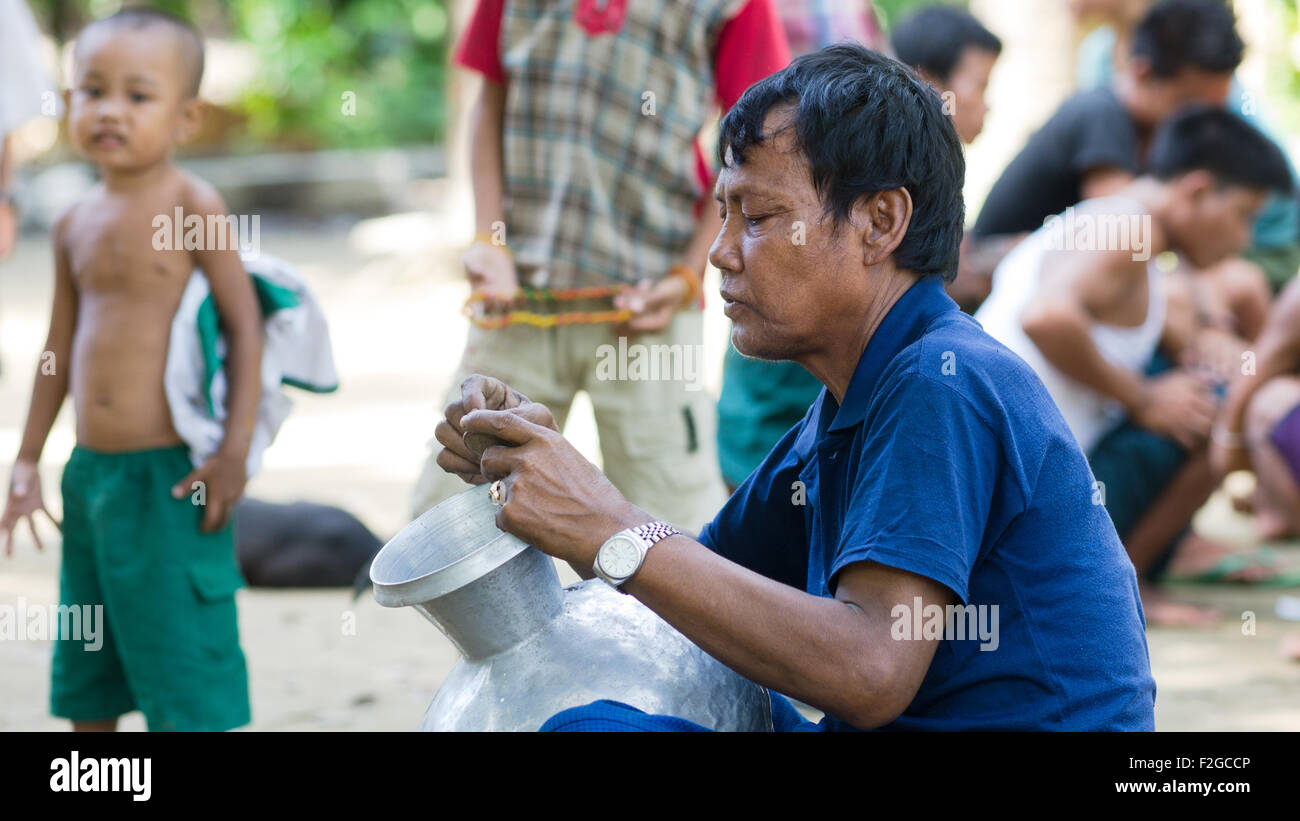 Uomo che ripara un contenitore di acqua in un villaggio lungo Lay Myo River in Western Stato di Rakhine, Myanmar. Foto Stock