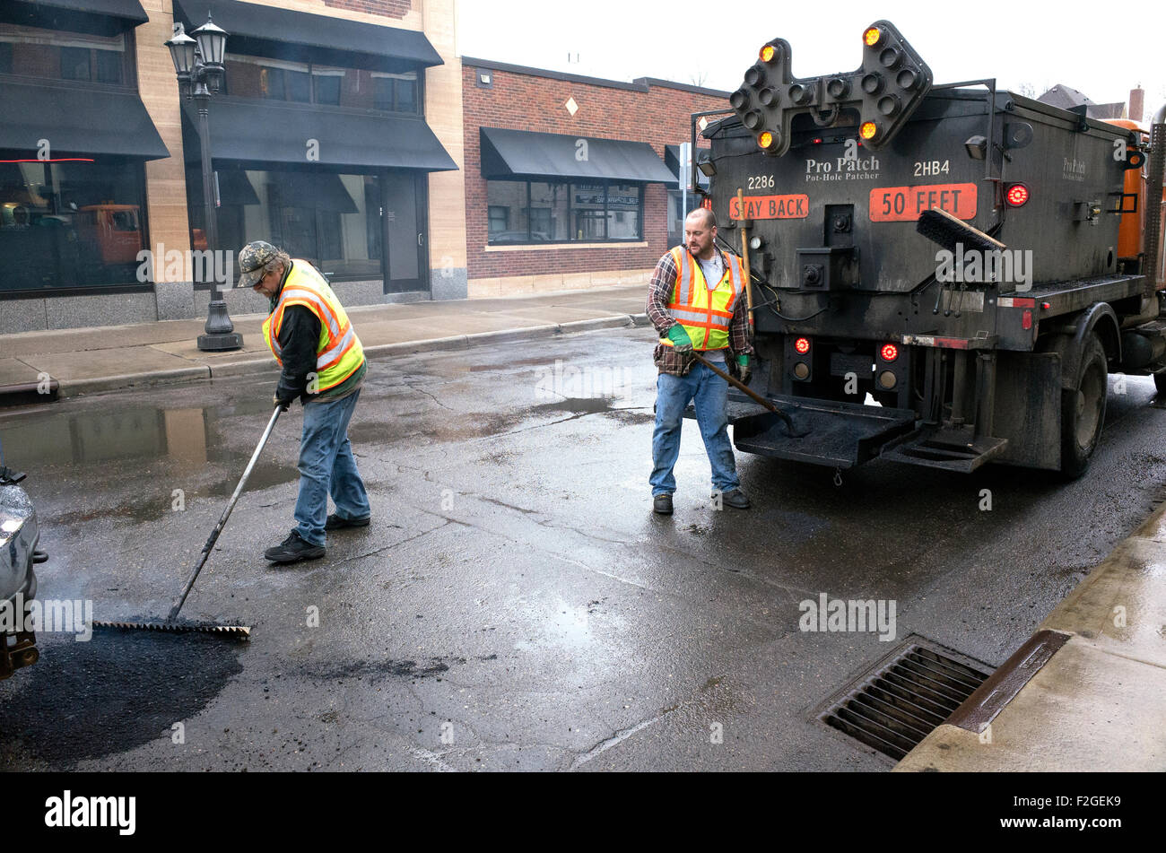 Gli uomini svolgono il loro rito annuale di riempimento del non finisce mai di minaccia delle buche per le strade della città. St Paul Minnesota MN USA Foto Stock