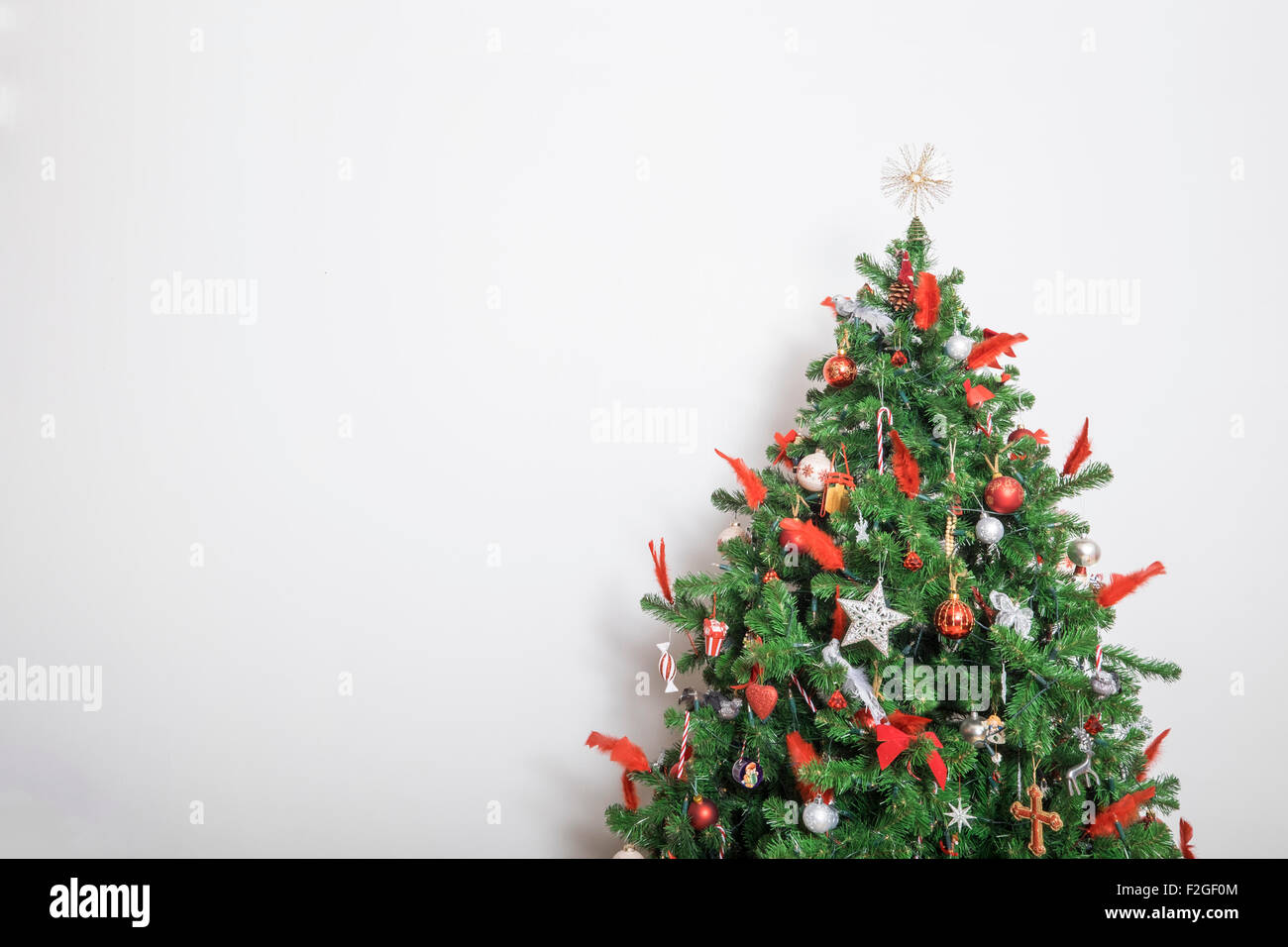 Bellissimo albero di Natale decorato contro un muro bianco Foto Stock
