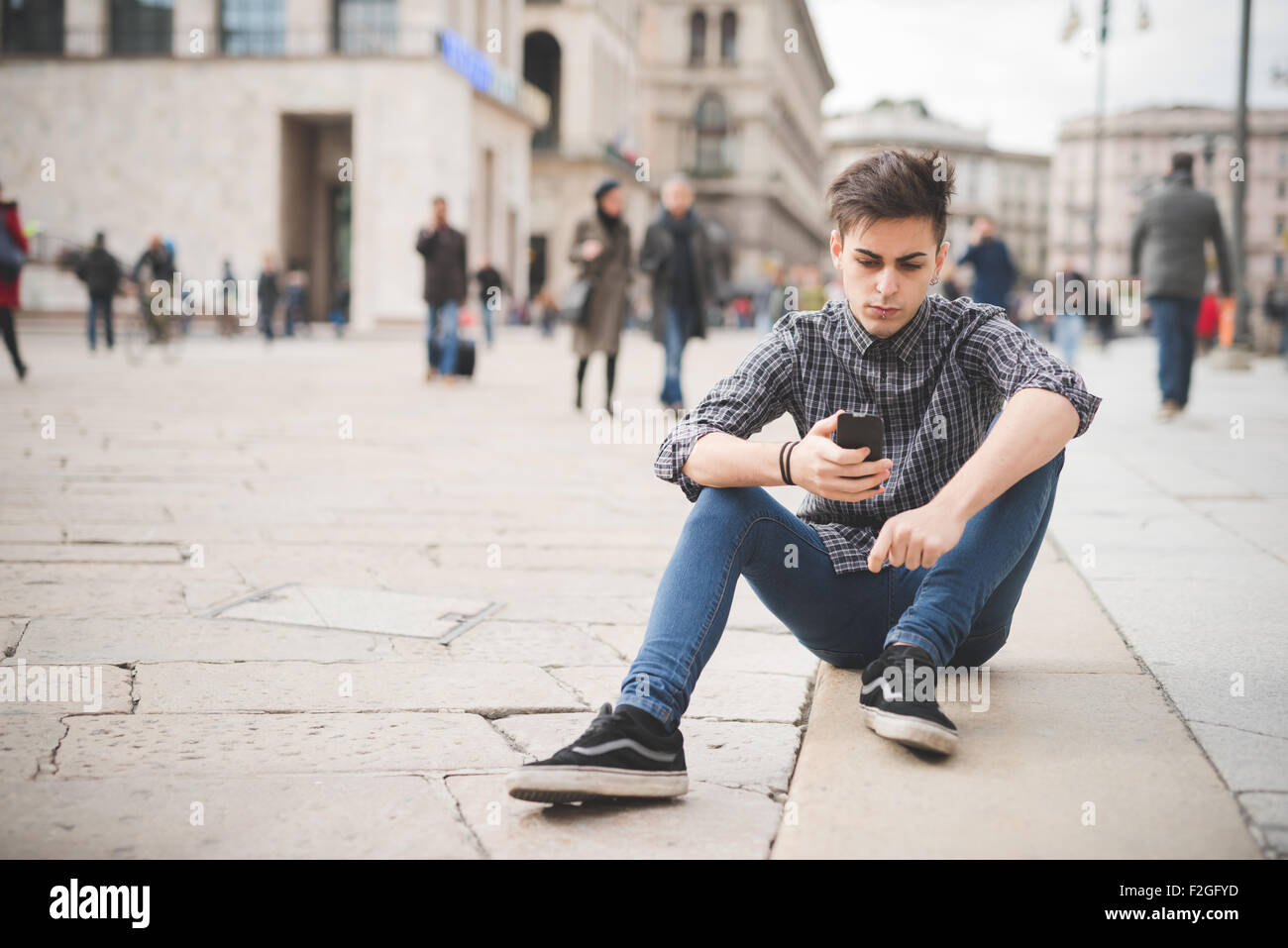 Alternativa giovane uomo bello con central labret e nostril piercing seduto  utilizzando uno smartphone connesso online - social network, comunicazione,  concetto tecnologico Foto stock - Alamy