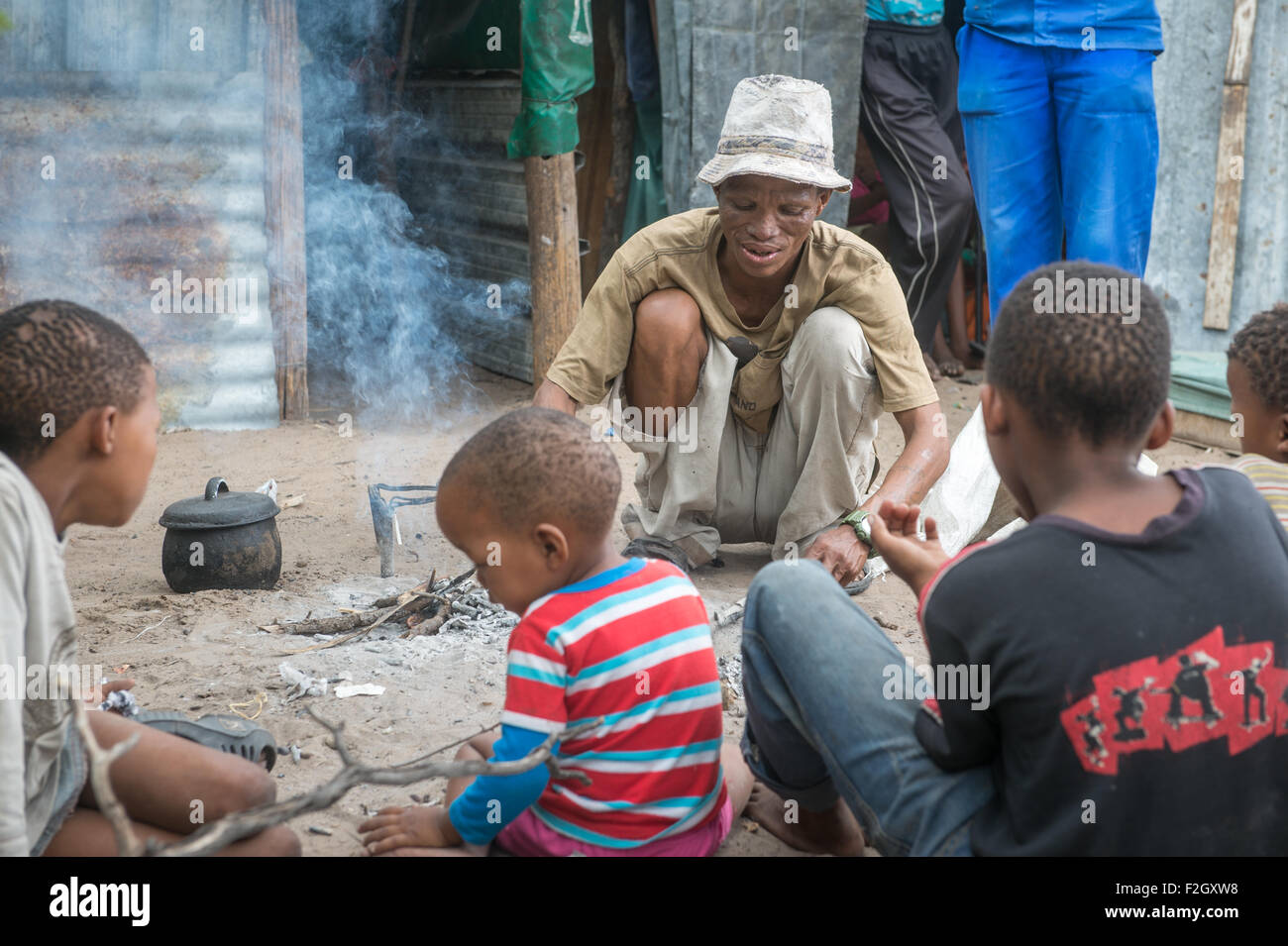 I Boscimani attorno a un fuoco nel loro villaggio in Botswana, Africa Foto Stock