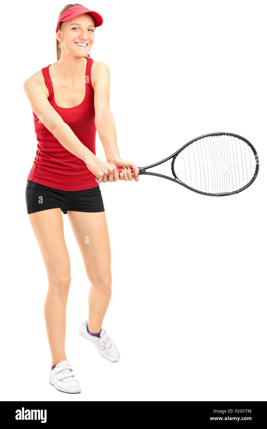 A piena lunghezza verticale di una femmina di giocatore di tennis oscillazione un rackuet e guardando la telecamera isolata su sfondo bianco Foto Stock