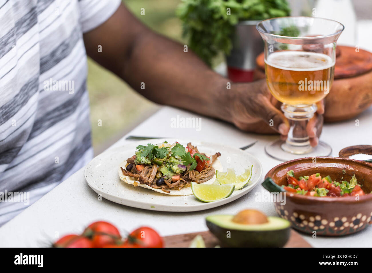 Una lenta manzo cotto brisket chili taco è servito a una persona in un tavolo da picnic con la birra. Foto Stock