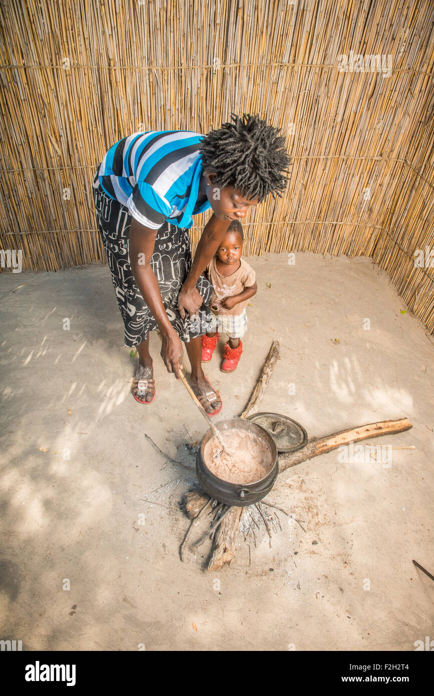 Donna africana e il bambino di agitazione il sorgo per la cena di famiglia in Botswana, Africa Foto Stock