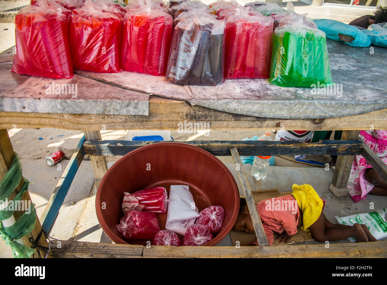 Insaccò fruttato bevande per la vendita in un mercato con una ragazza dorme sotto il tavolo in Botswana, Africa Foto Stock