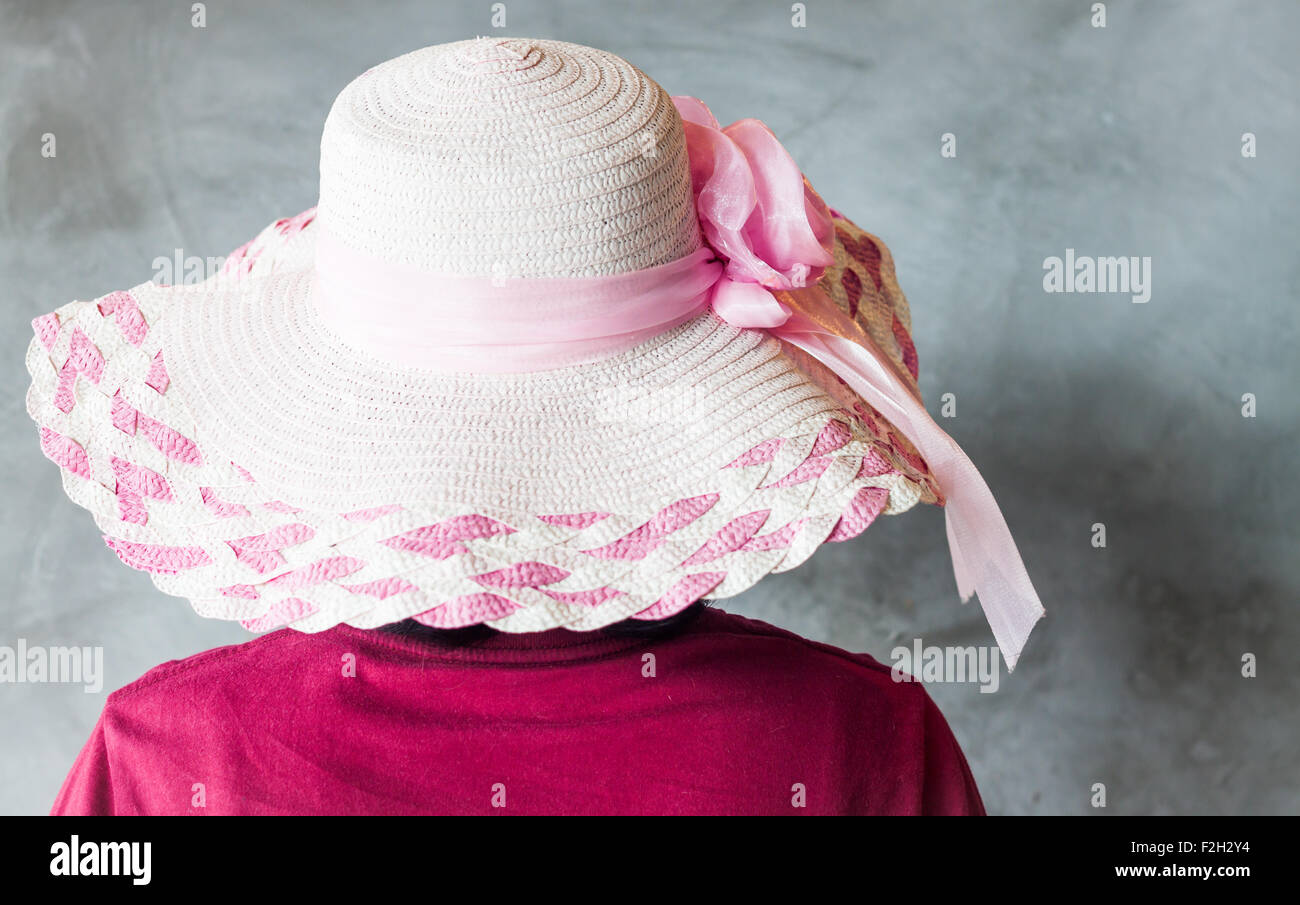 Donna con cappello rosa su sfondo grigio, stock photo Foto Stock