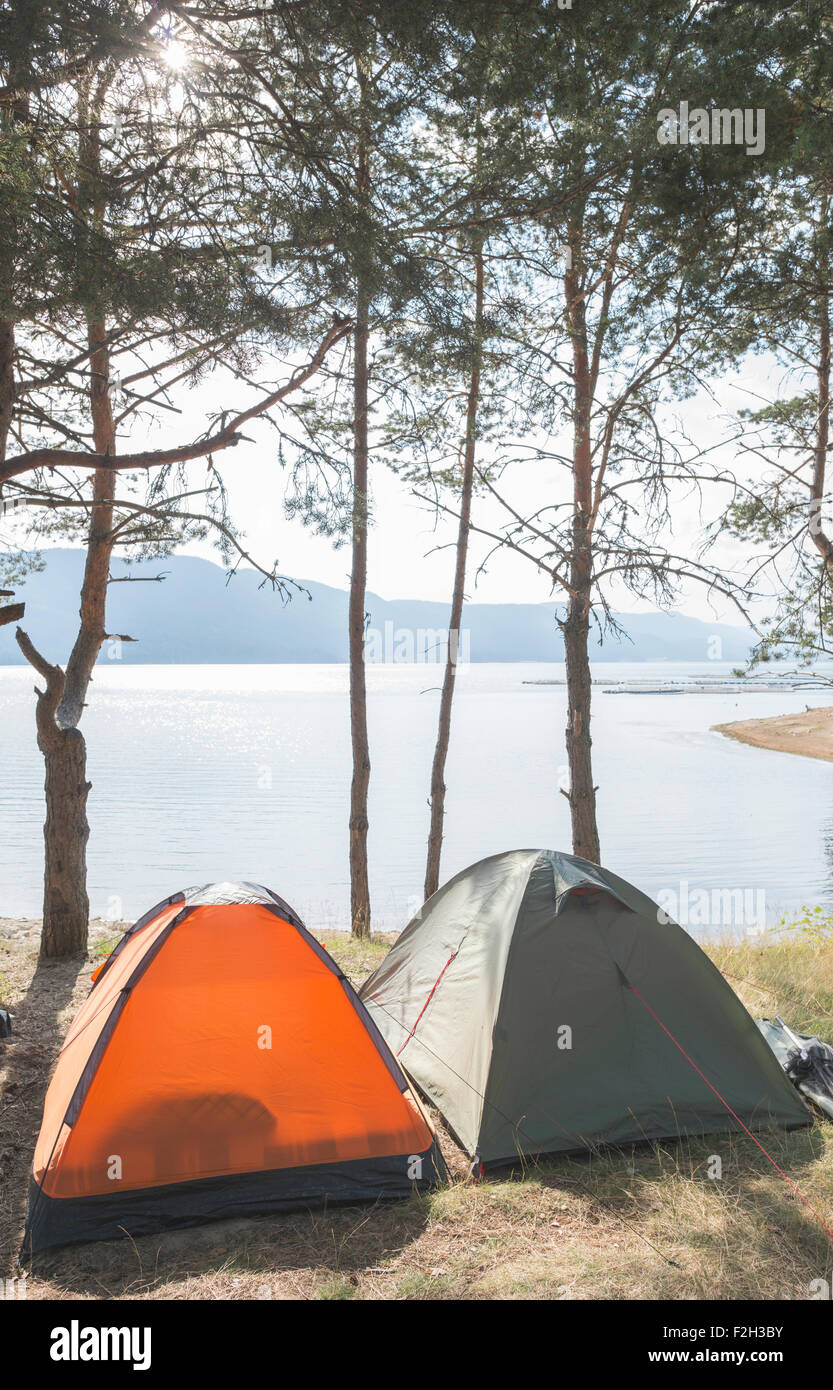 Le tende nella foresta di fronte lago di montagna Foto Stock