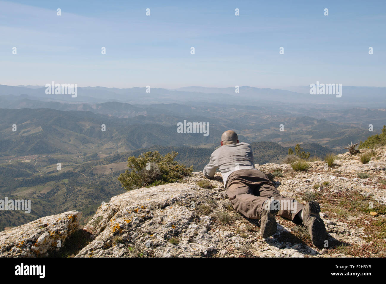 Uomo sdraiato guardando al paesaggio, con montagne di nebbia Foto Stock