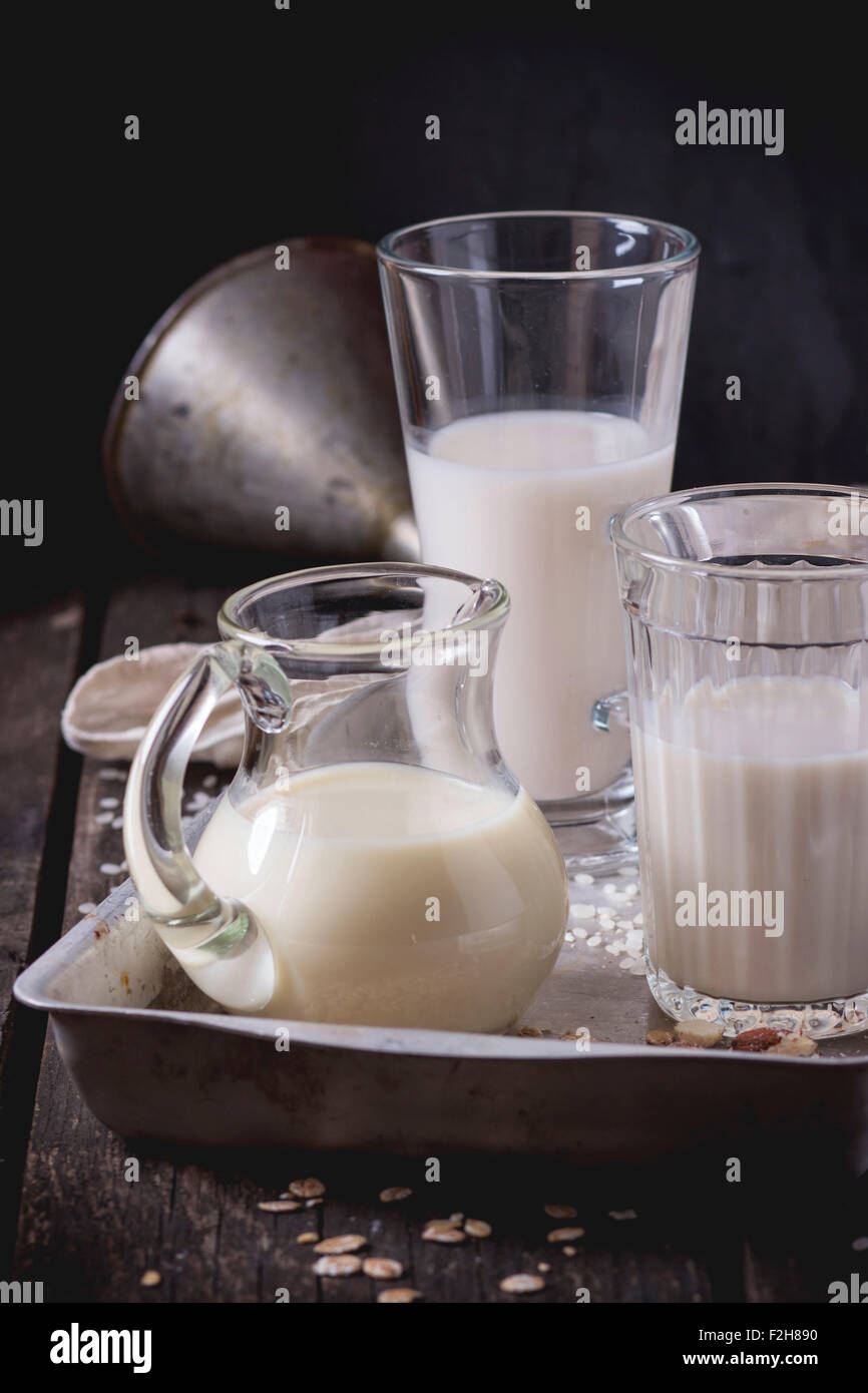 Set di non-latte (latte di riso, latte di mandorla e Latte di avena) in bicchieri di vetro e la brocca sulla vecchia vaschetta di alluminio con grani di riso, avena fla Foto Stock